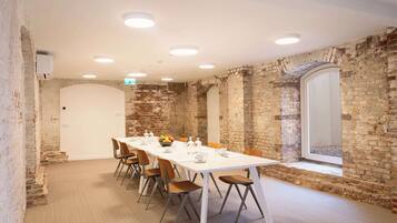 A conference room with a long table, chairs, and a brick wall.