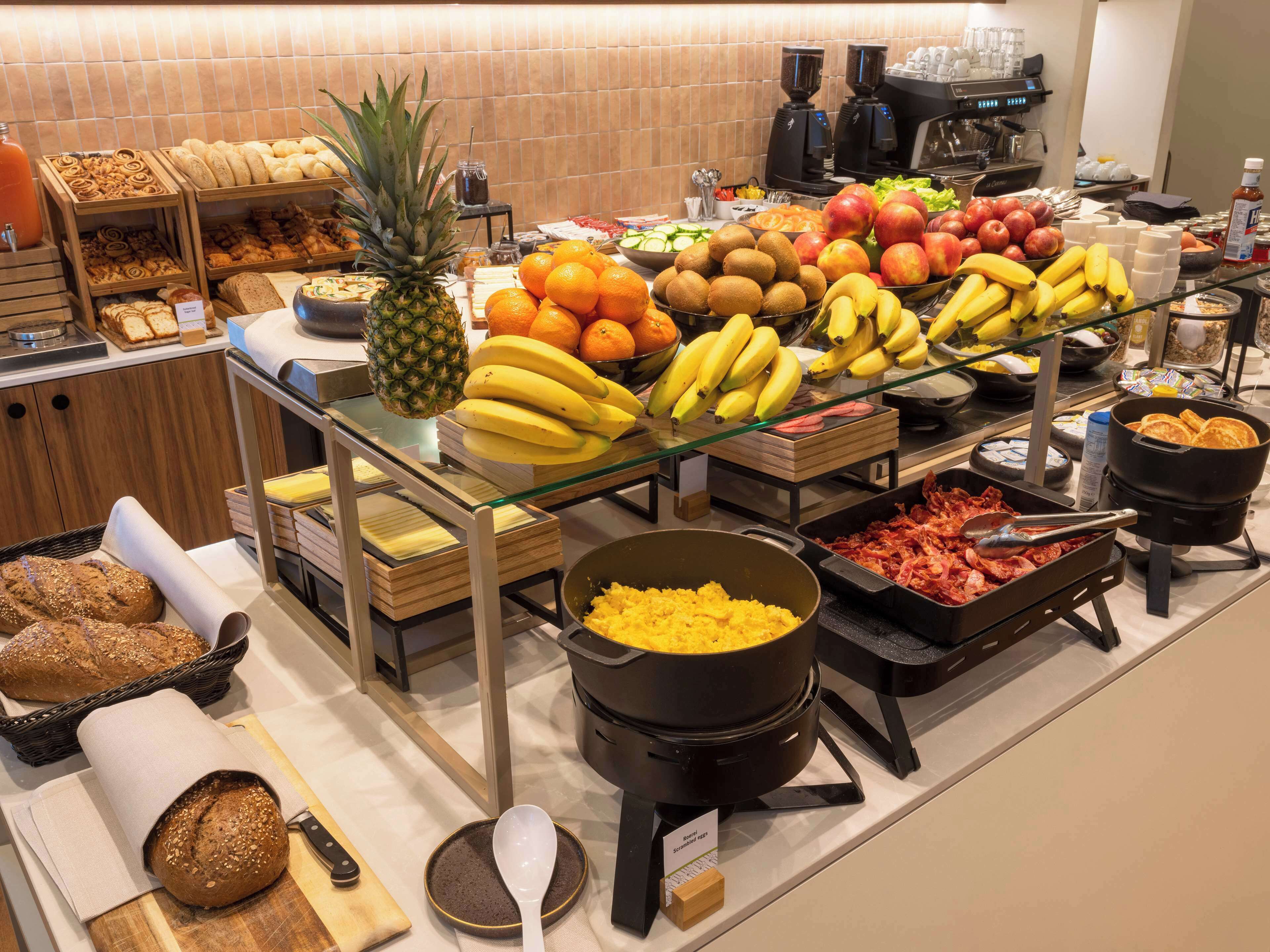 En buffé med ett varierat utbud av mat, inklusive frukt, bröd och olika frukostalternativ.