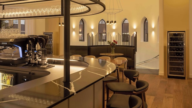 Zona de bar moderna con una máquina de café, asientos y un enfriador de vino.