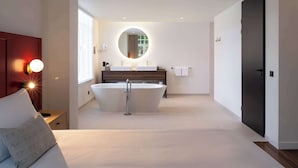 Un baño moderno con una bañera independiente, un espejo grande y un tocador con dos lavamanos.