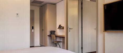 A hotel room with a bed, a desk, a chair, and a television.