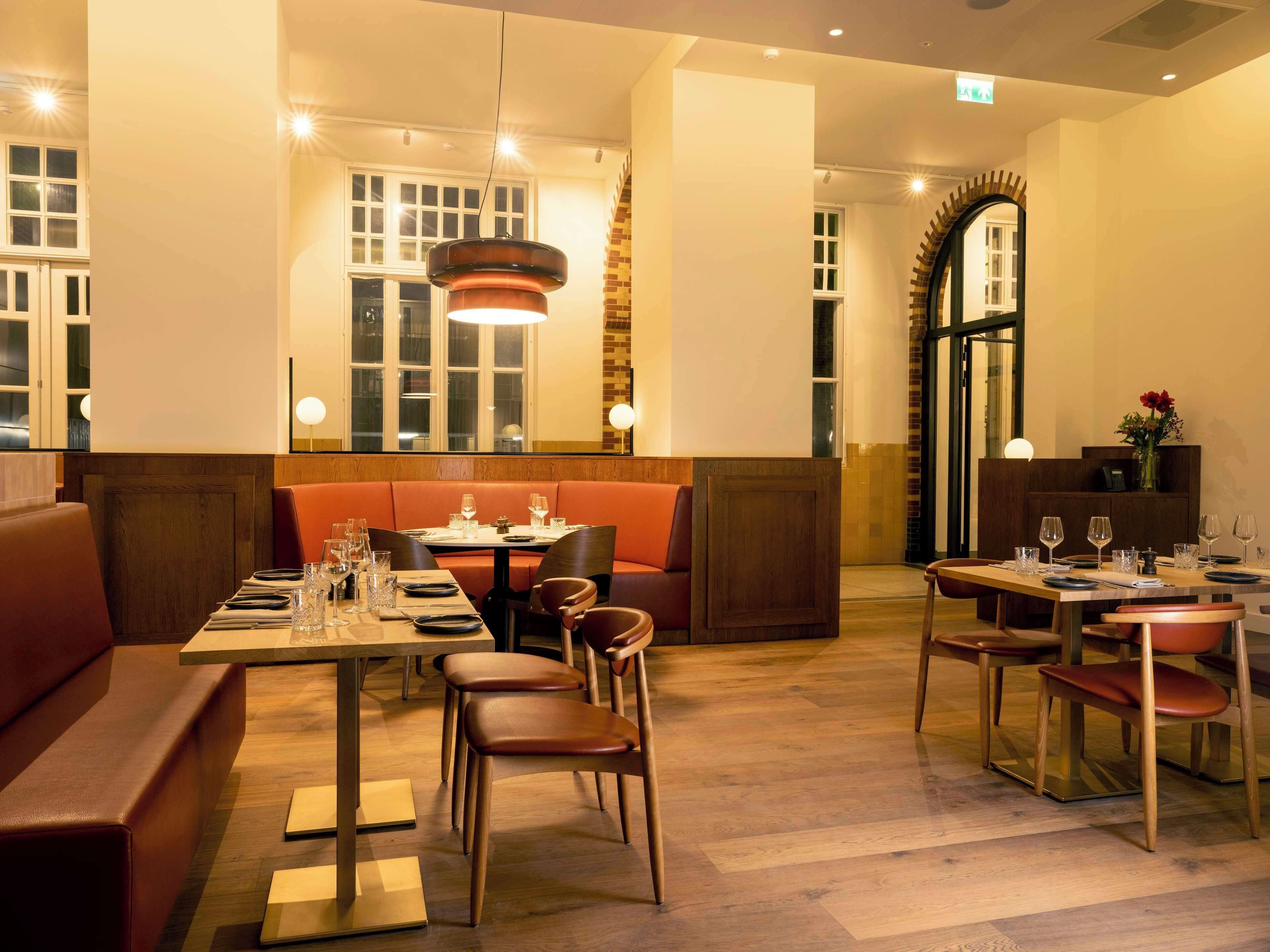 A restaurant with wooden flooring, tables set for dining, and a warm, inviting atmosphere.