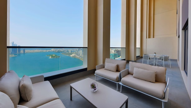 Una sala de estar moderna con un sofá, una mesa de centro y vistas a un paisaje urbano y una masa de agua.