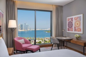 A hotel room with a large window offering a city view, a bed, a desk, and two chairs. - DoubleTree by Hilton Sharjah Waterfront Hotel & Residences (Sharjah)