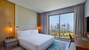 Una habitación de hotel moderna con una cama grande, un escritorio y vistas a la ciudad y al agua.