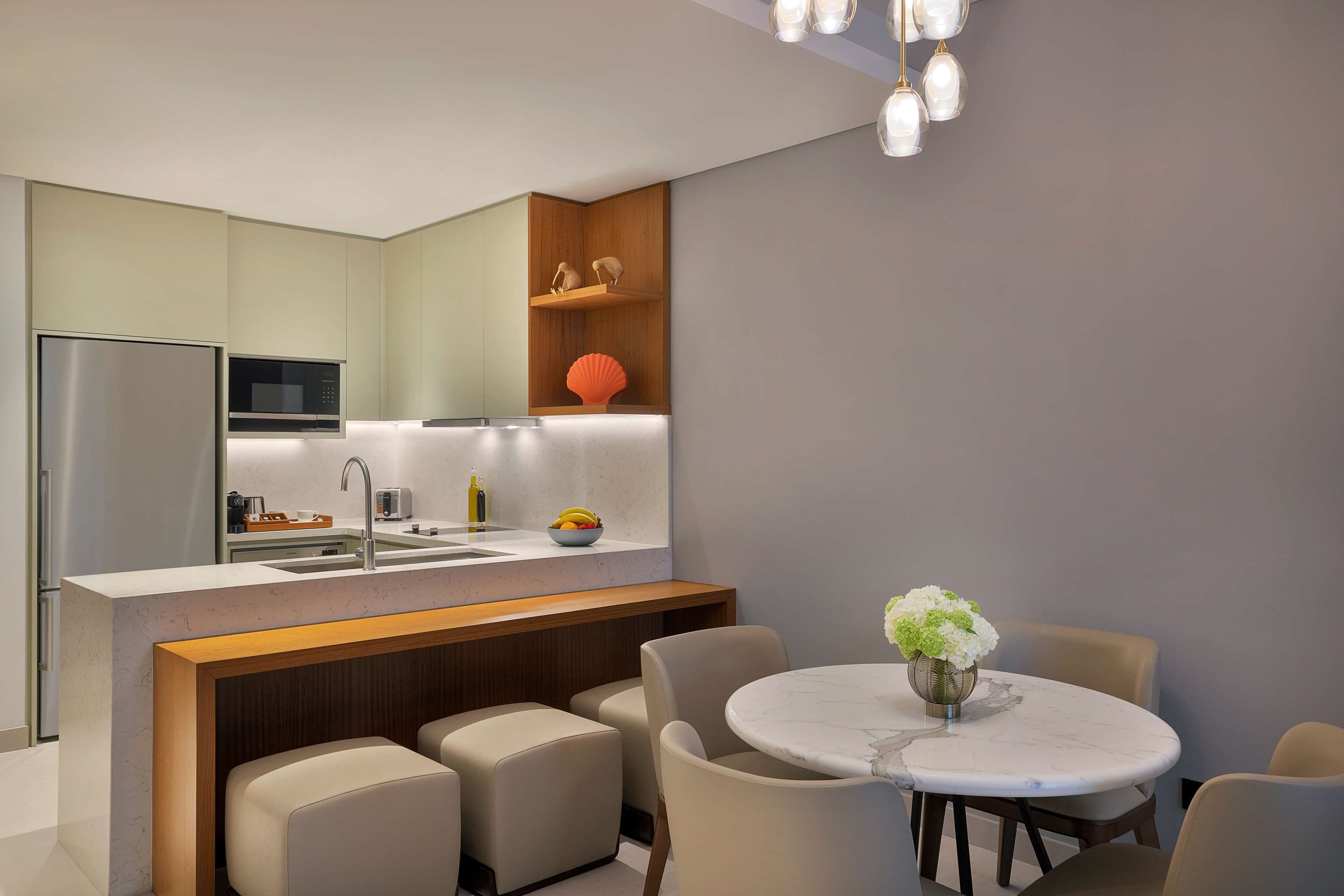 A modern kitchen with a central island, a dining area with a round table, and a built-in microwave.