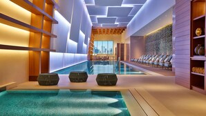 Una piscina interior moderna con vistas a la ciudad, sillas de descanso y un muro con diseño.