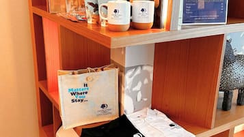 A display of DoubleTree-branded items including mugs, notebooks, and bags, with a wooden shelf and a signboard.