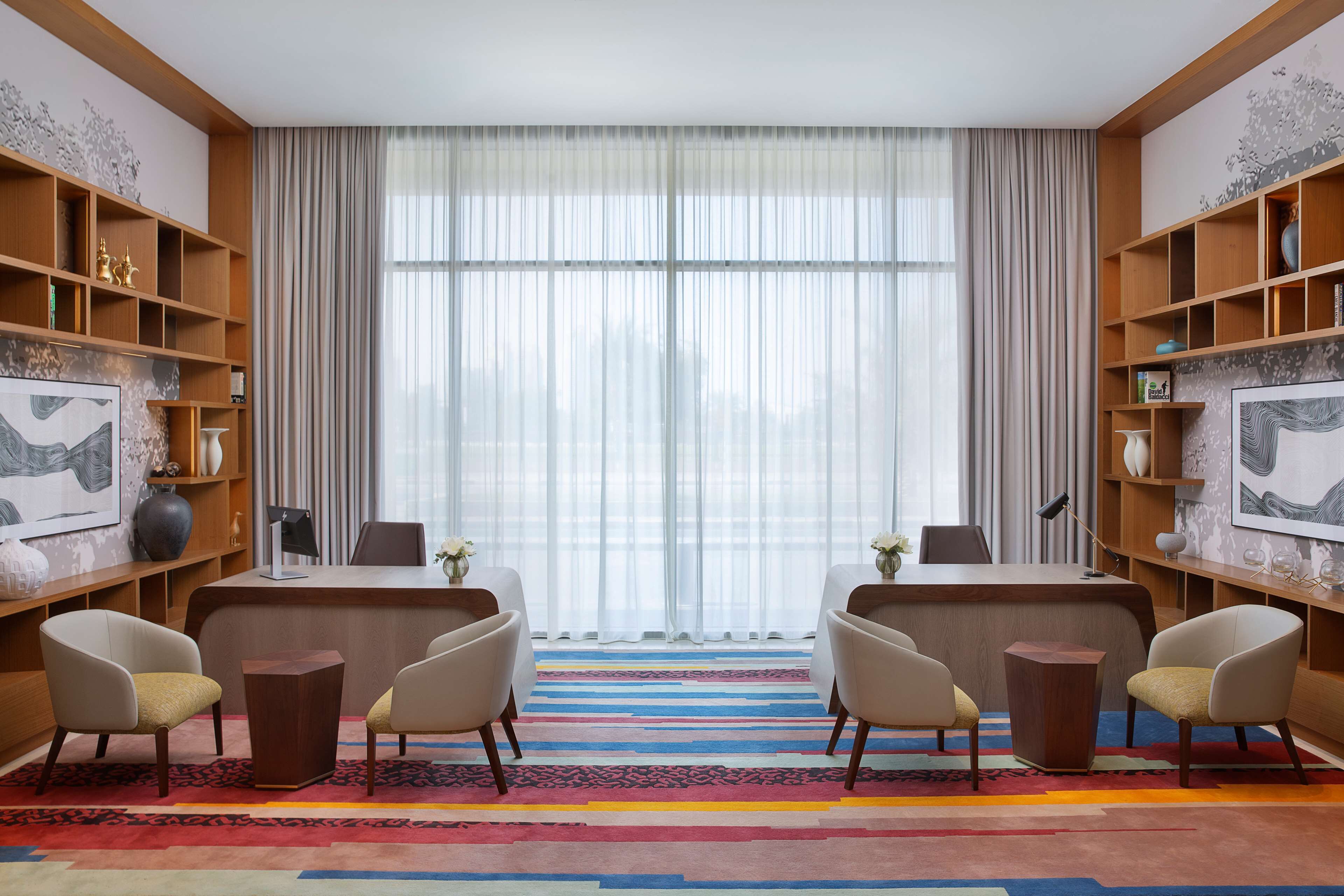 A modern office space with a large desk, two chairs, and a colorful striped carpet.