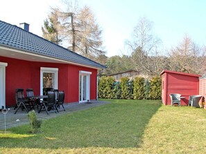 A red house with a patio, a shed, and a well-maintained lawn.