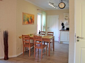 Et spiseområde med et træbord og stole, et billede på væggen og et køkken i baggrunden.