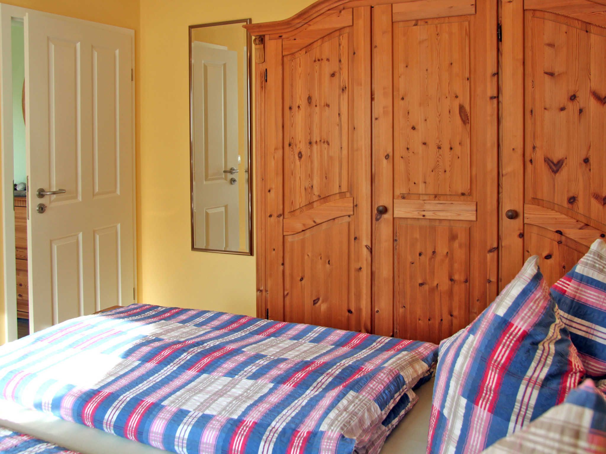 Ein Schlafzimmer mit einem Bett, einem Holzschrank und einem Spiegel.