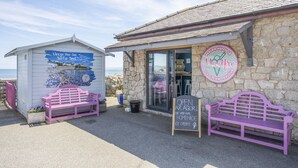 Gelateria a la vora del mar amb parets de pedra, dues banquetes roses i una pissarra anunciant gelats casolans.
