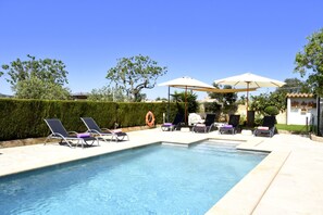 Une piscine avec des chaises longues et des parasols.