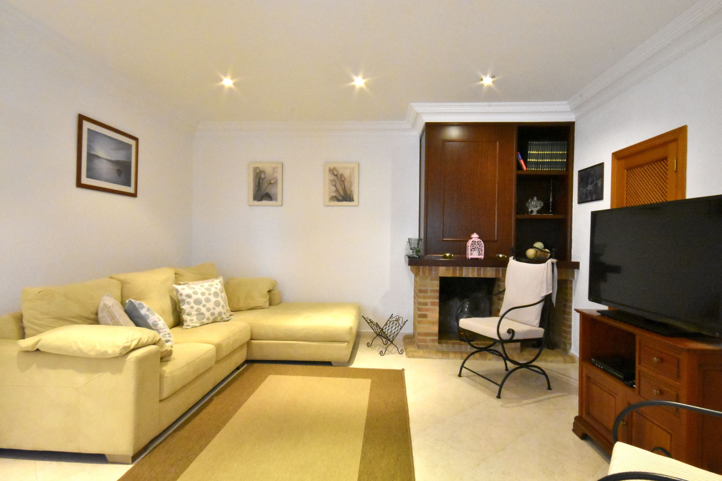 A living room with a sofa, a television, a fireplace, and a bookshelf.
