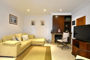 Una sala de estar con sofá, televisión, chimenea y estantería.