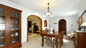 A dining area with a wooden table and chairs, a cabinet with glass doors, and a chandelier. - 44262 Finca Els Xiprers (Porreres)