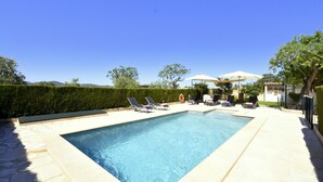 A rectangular swimming pool with a stone border, surrounded by lounge chairs and umbrellas. - 44262 Finca Els Xiprers (Porreres)