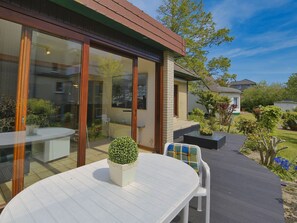 A patio area with a round table and chairs, a potted plant, and a glass door leading to a room. - N 40 GH 4-room Terr. (BC.n5) - Stranddomicil Steiner - Guesthouses (Büsum)