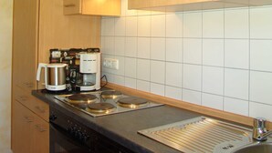 A compact kitchen with a coffee maker, a kettle, and a dishwasher.