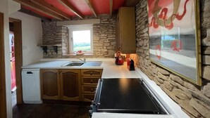 Una cocina con pared de piedra, muebles de madera, una ventana y encimera negra.