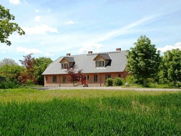 A two-story house with a sloped roof, a front porch, and a well-maintained lawn.