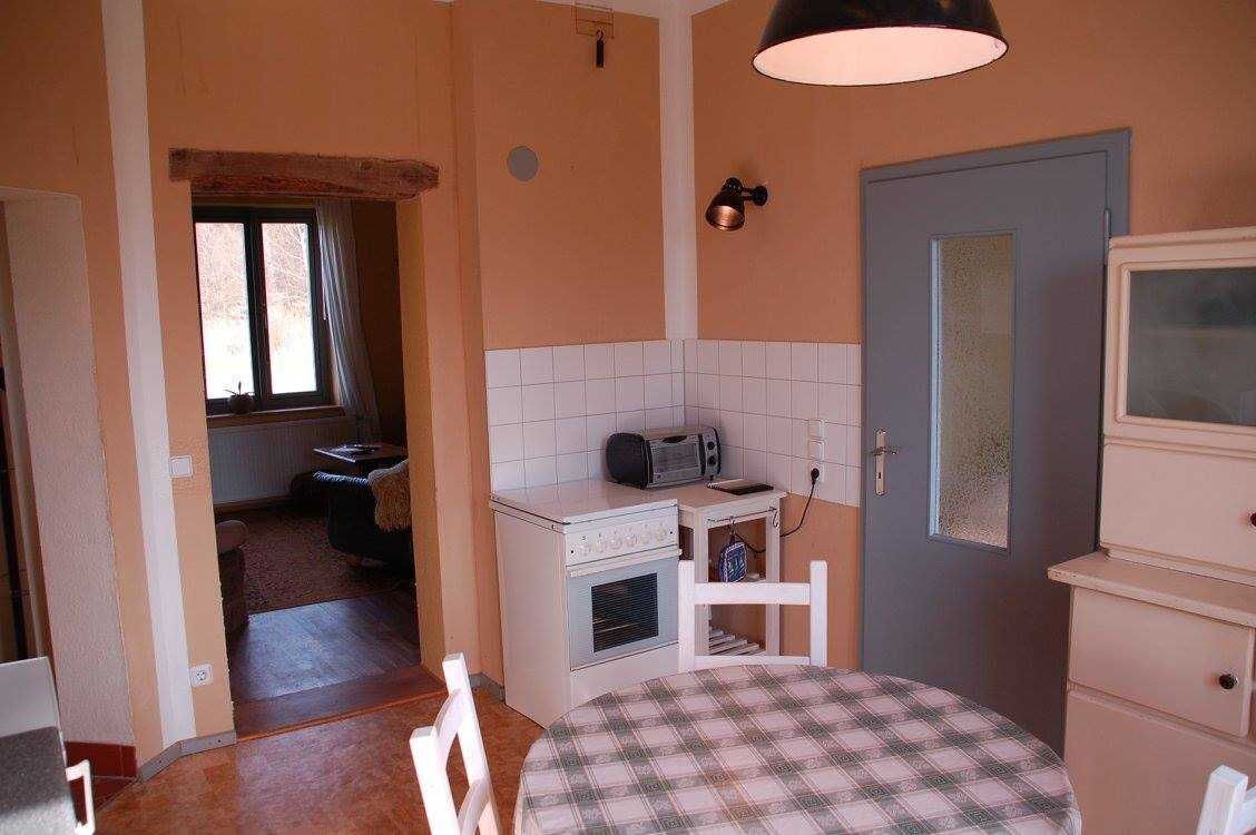 Une cuisine compacte équipée d’un four à micro-ondes, d’un petit four et d’un évier. On y trouve une table à manger recouverte d’une nappe à carreaux.