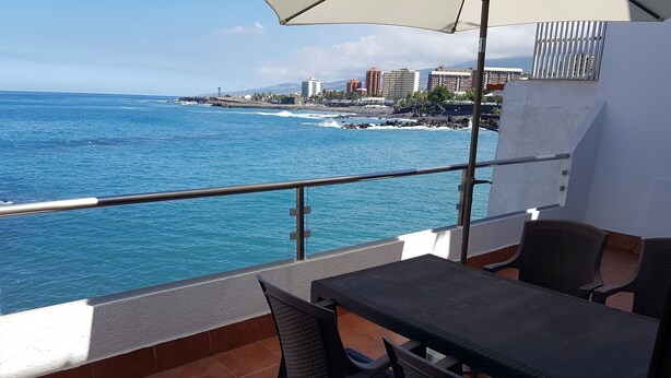 Un balcon avec vue sur l’océan et le paysage urbain.