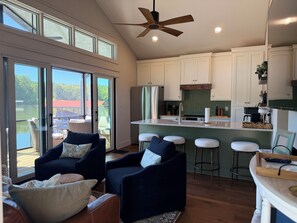 A modern kitchen with a central island, bar stools, and a ceiling fan.