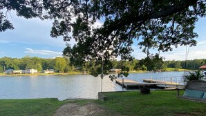 Vista al lago con un muelle, zona de césped y una silla mecedora.