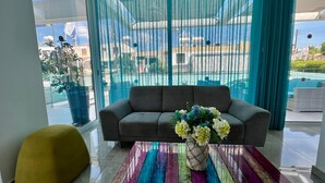 Un salon moderne avec un canapé gris, une table basse colorée et un pouf jaune.