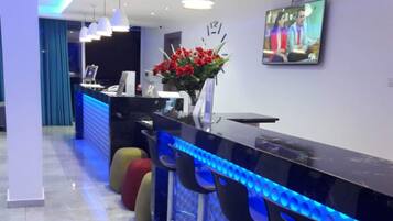 A modern bar area with a black countertop, blue LED lighting, and three black bar stools.