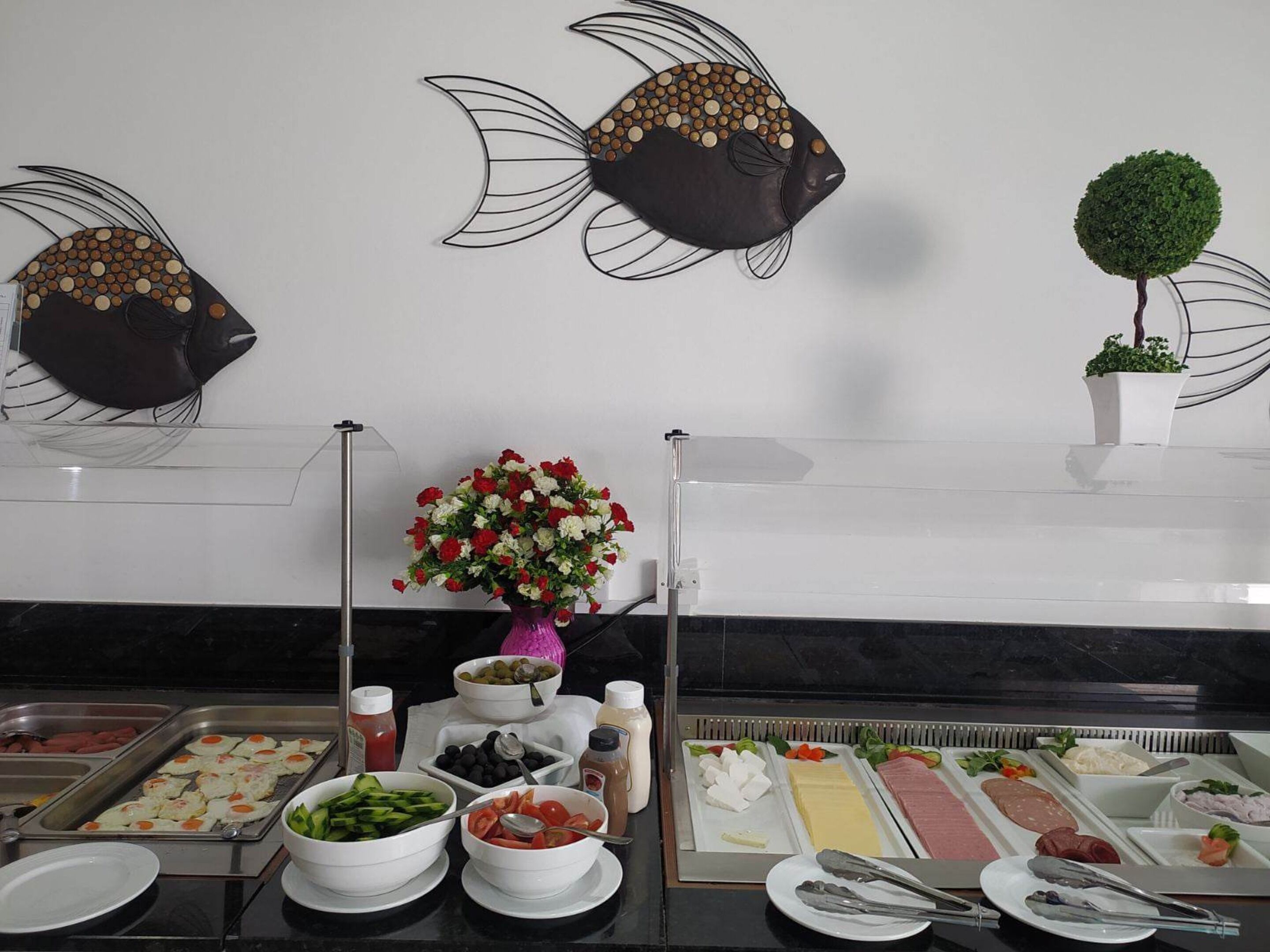 A buffet setup with various food items and a decorative fish wall art.