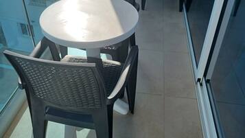 Un balcón con una mesa redonda y cuatro sillas.