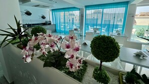 Un intérieur d’hôtel moderne comprenant un espace repas, une cuisine et un balcon agrémenté de plantes et offrant une vue agréable.