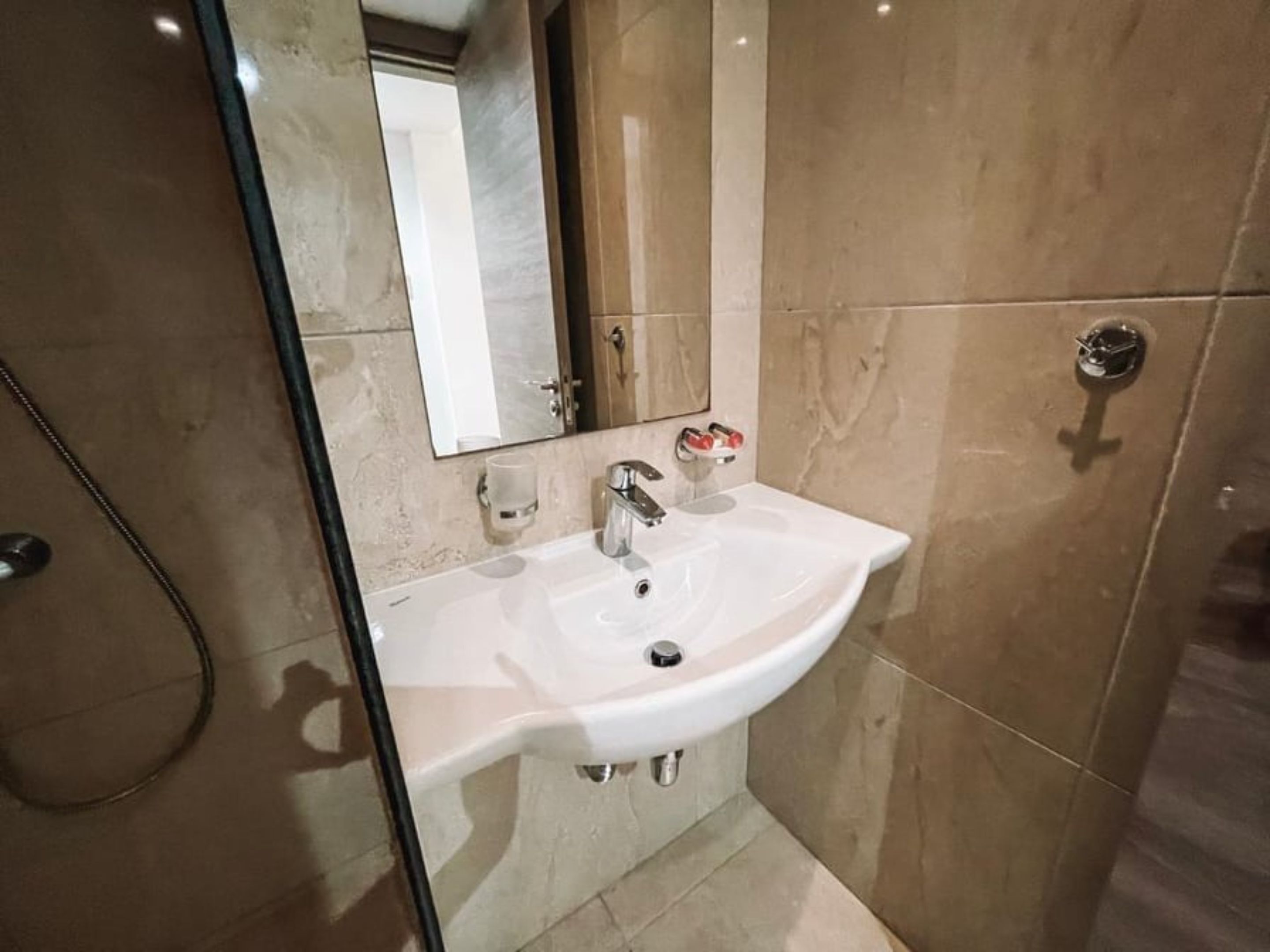 Une salle de bain avec un lavabo blanc, un miroir et un espace douche.