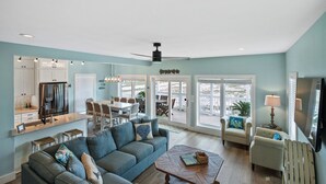 A spacious living room with a sofa, coffee table, and a dining area with chairs and a table. - Dog Friendly Private Beach House in Beautiful Fort Morgan, Alabama!  (Gulf Shores)