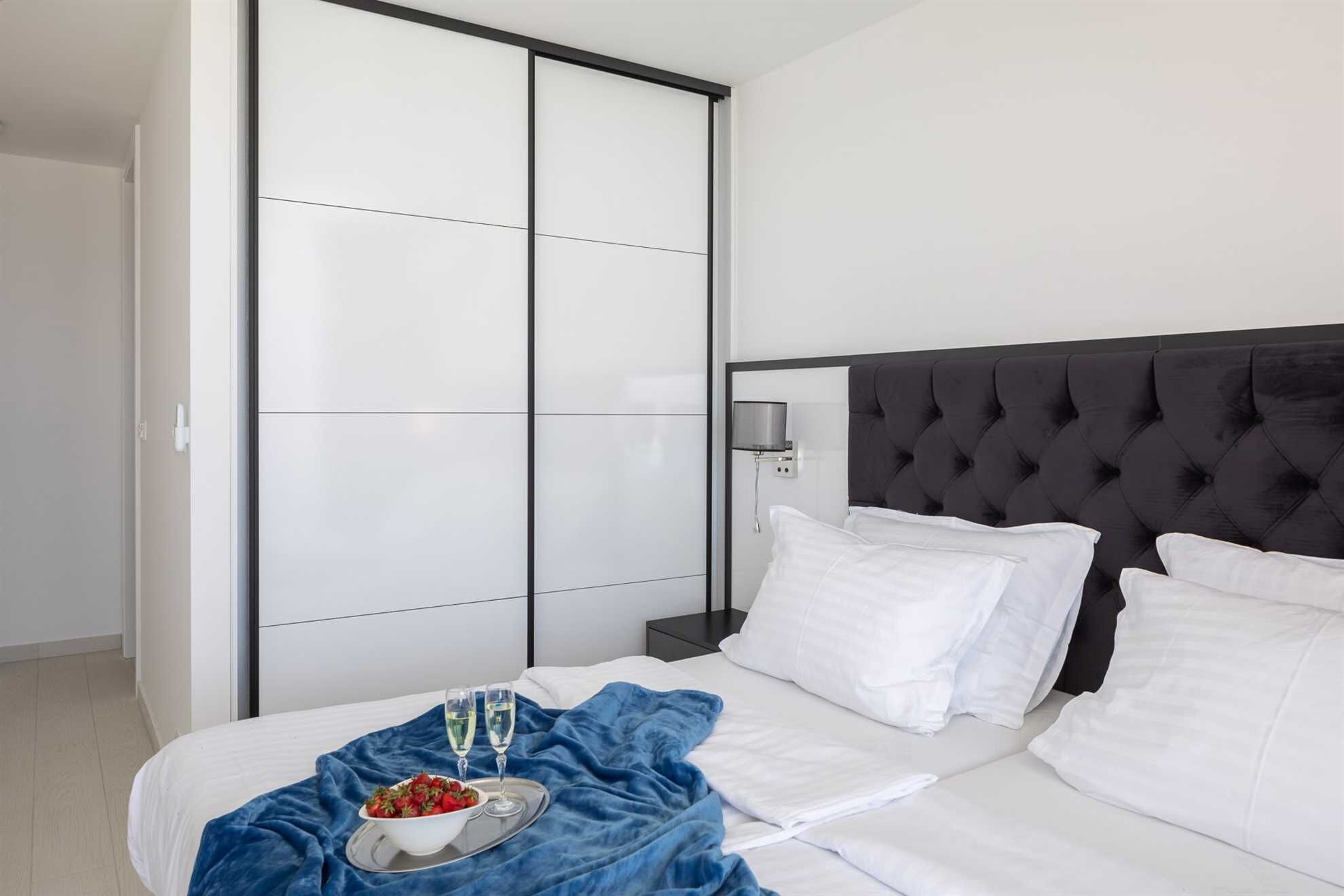 Una habitación de hotel con cama, mesita de noche, armario y velador.