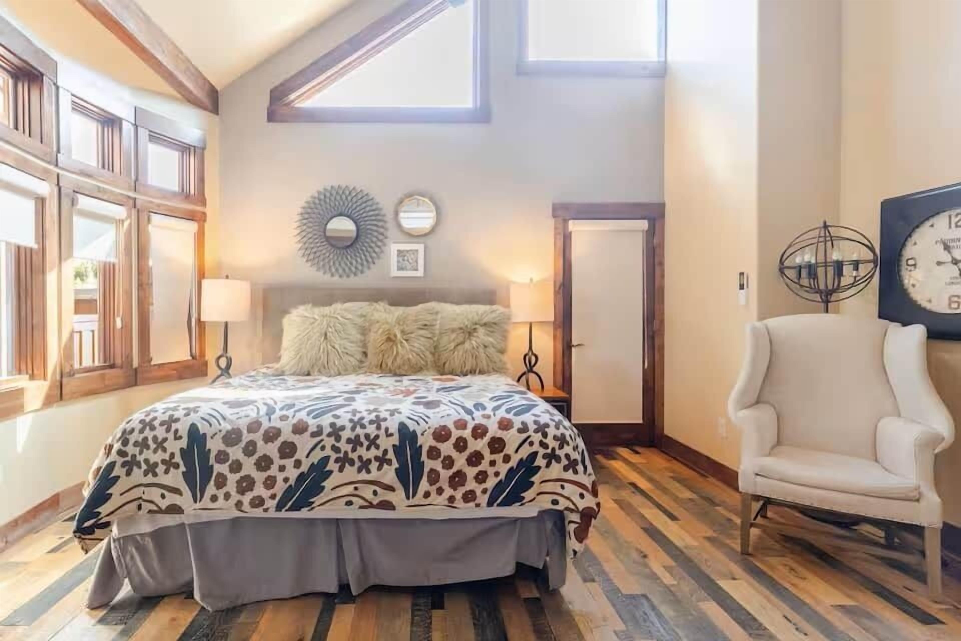 A bedroom with a bed, a chair, a clock, and a window.