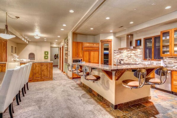 A spacious kitchen with a large island, wooden cabinets, and bar stools.