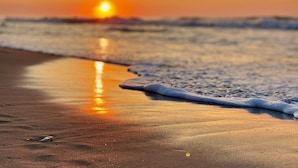 A beach scene with a sunset, waves, and wet sand. - Ocean Lakes-Sleeps 6-Free Golf Cart Included-Pet-Friendly (Myrtle Beach)