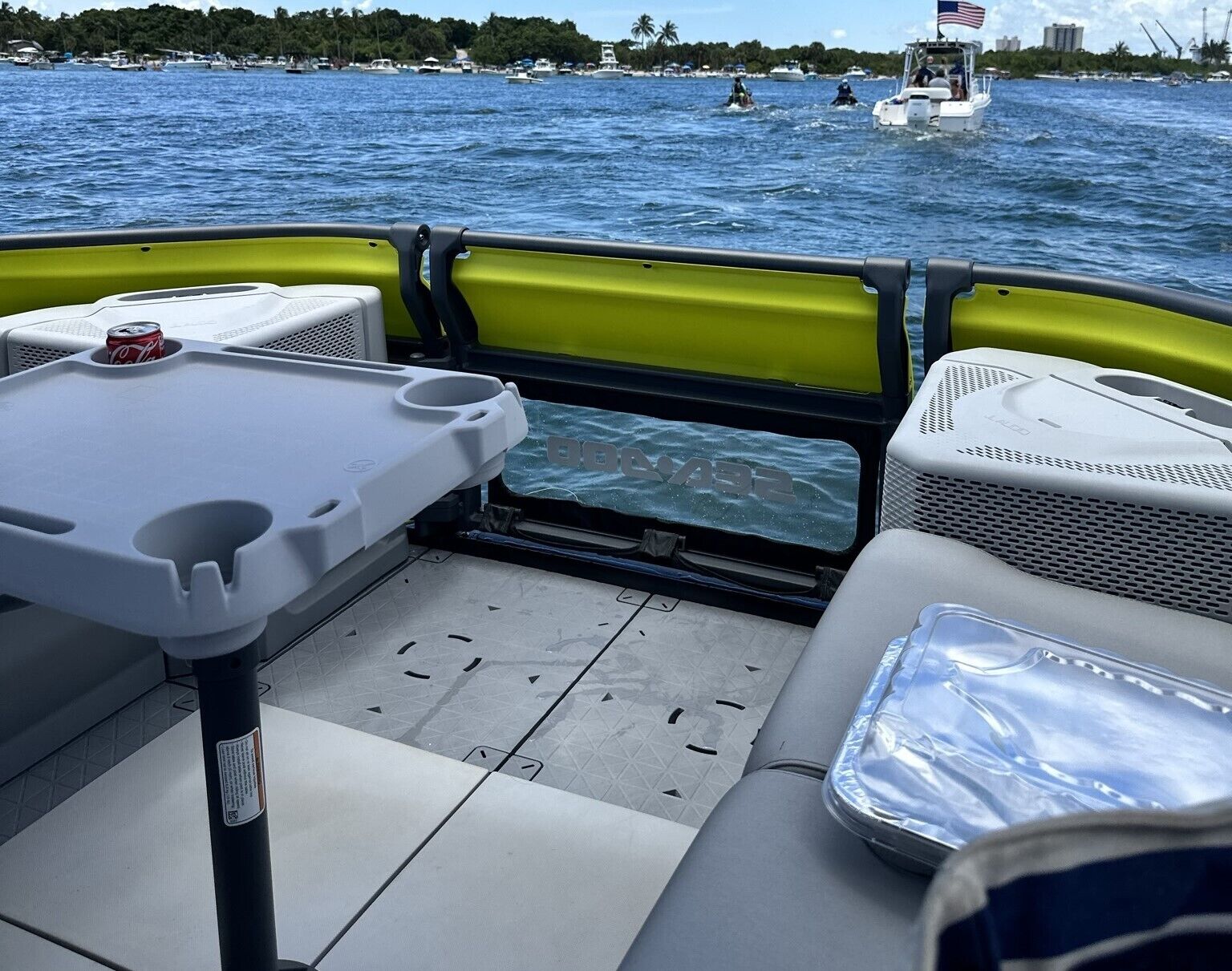 A boat's interior with seating, a table, and a view of the water.