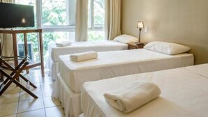 A hotel room with two single beds, a TV on a wooden stand, a desk with a chair, and a window with curtains. - Tangoinn Bed and Brewery (Puerto Iguazú)