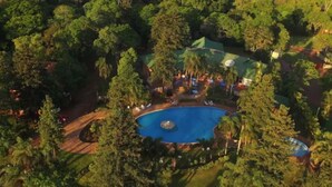 An aerial view of a resort with a central swimming pool, surrounded by dense trees and a few buildings. - Tangoinn Bed and Brewery (Puerto Iguazú)