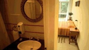 A bathroom with a sink, mirror, and hand soap dispenser. - Tangoinn Bed and Brewery (Puerto Iguazú)
