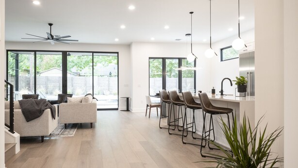A modern kitchen with bar stools, large windows, and a ceiling fan. - Luxury New Build, Private Pool and Spa, Sleeps 10 all King, 4 min to Dt (Austin)