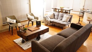 A living room with a sofa, armchair, coffee table, and a dining area with a table and chairs. - The Tranquility Den (NRG,City Centre, Galleria) (Houston)