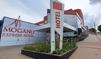 Señal de hotel con el nombre 'MOGANO EXPRESS HOTEL' y una estructura de edificio moderno al fondo.