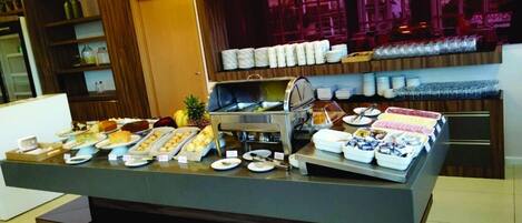 A buffet setup with various food items and utensils.
