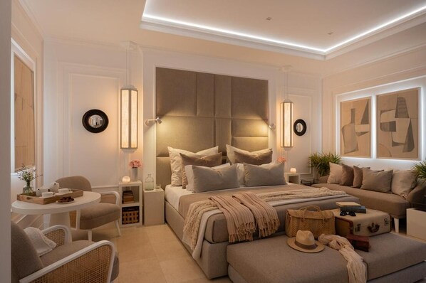 Une chambre moderne avec un grand lit, des tables de chevet, un canapé et une petite table ronde avec des chaises.